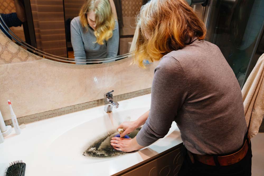 women with a plunger unclogging the sink